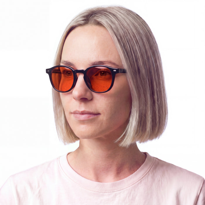 Vrouw draagt de zwarte anti blauw licht bril met oranje glazen