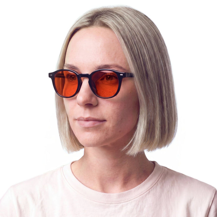 Vrouw draagt de zwarte anti blauw licht bril met oranje glazen