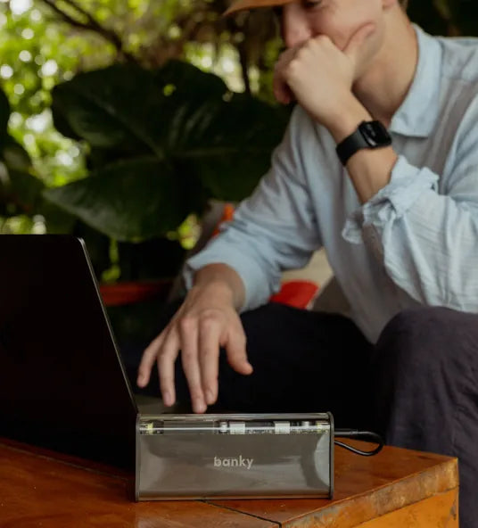 Man aan tafel met zijn laptop en de Banky laptop powerbank 100W