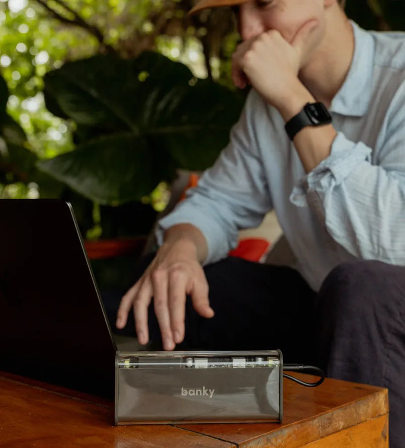 Man aan tafel met zijn laptop en de Banky laptop powerbank 100W